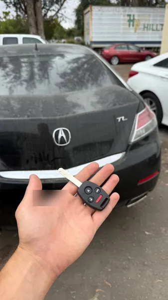 Acura remote head key held behind a black Acura TL