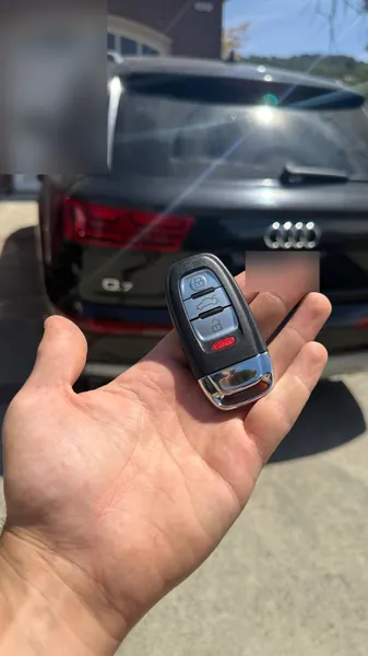 Audi smart key held behind a black Audi Q7