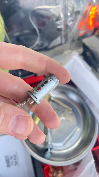 Car lock cylinder held over a magnetic parts tray during repair