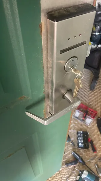 Commercial mortise lever lock with keys in the cylinder on a green door