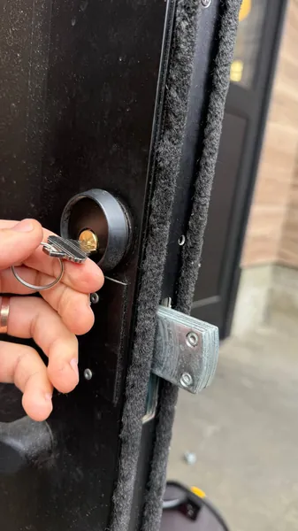 Key turning a lock cylinder on a black door