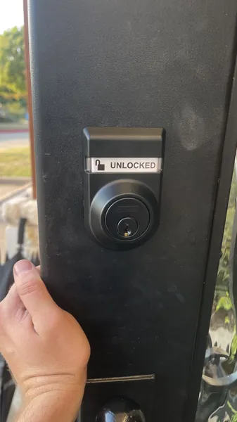 Black single-cylinder deadbolt with an UNLOCKED status window on a black door
