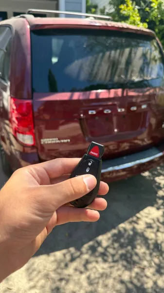 Dodge fobik key held behind a red Dodge minivan