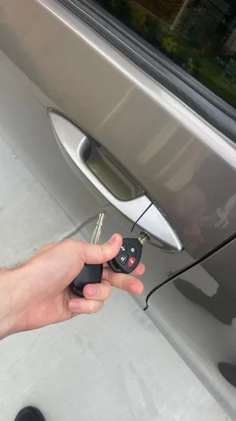 Flip key turned in the driver door lock of a silver car