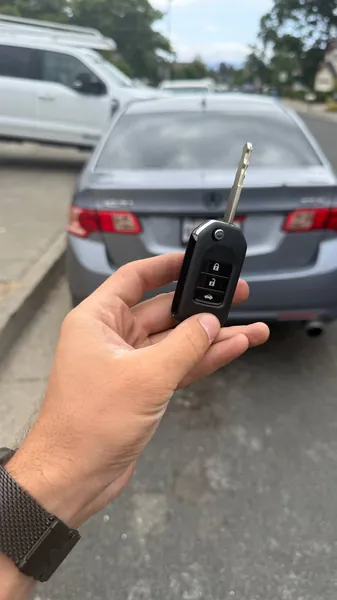 Flip key held behind a gray sedan