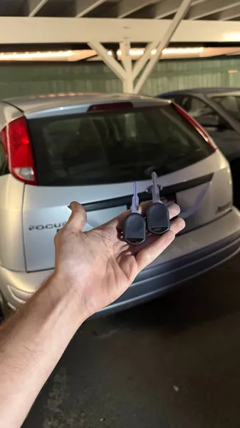 Two car keys held behind a silver Ford Focus
