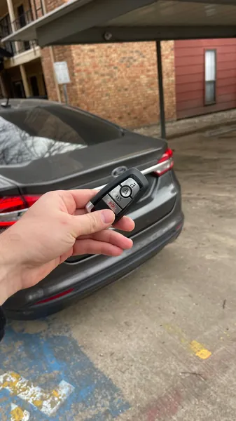 Ford smart key held behind a gray Ford sedan in an apartment carport