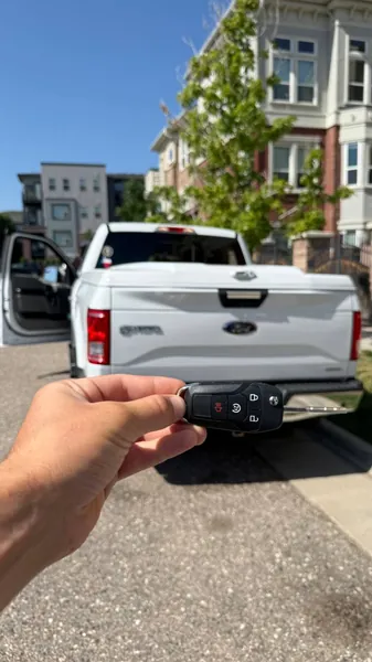 Ford key held behind a white Ford pickup