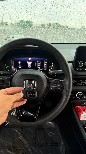 Honda smart key held at the steering wheel on a rainy day