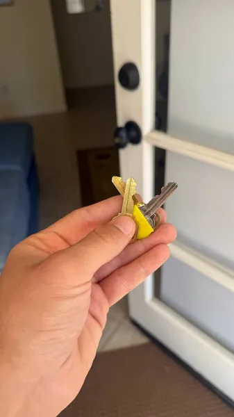 Two house keys held up at an open front door