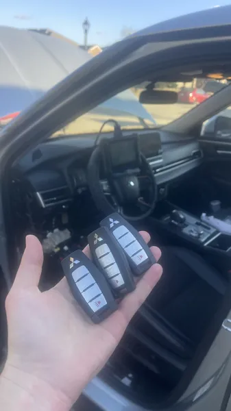 Three Mitsubishi smart keys held up inside the car