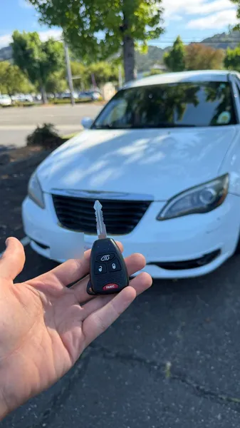 Remote head key held in front of a white sedan