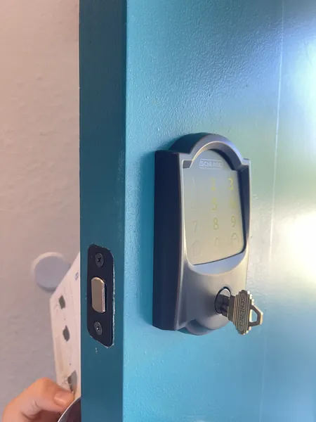 Schlage touchscreen deadbolt with a Schlage key in the cylinder on a blue door