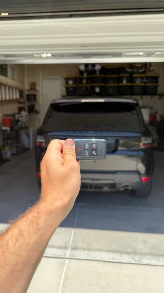 Smart key held up behind an SUV parked in a garage