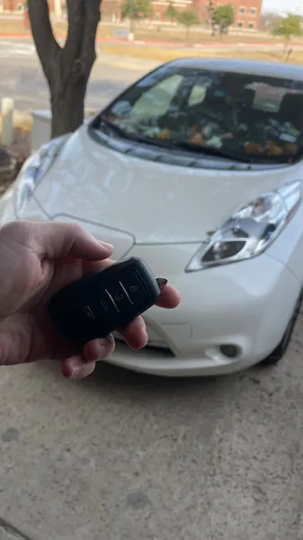 Aftermarket smart key held in front of a white compact hatchback
