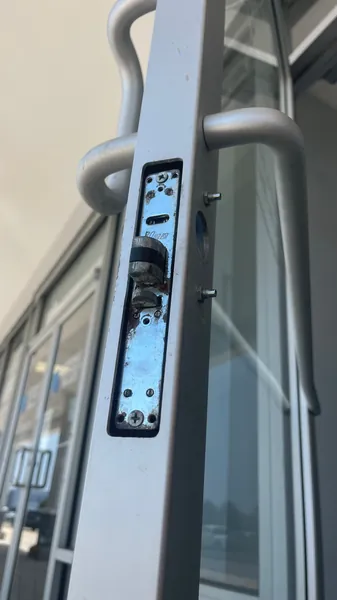 Aluminum storefront door with the mortise lock body exposed in the stile