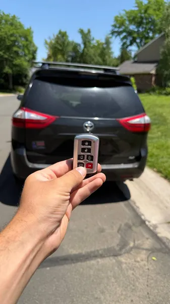 Toyota smart key held behind a black Toyota minivan