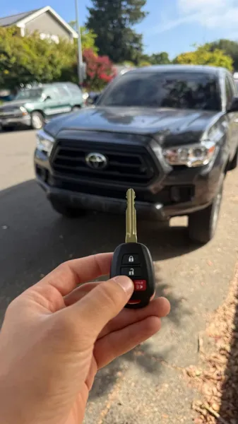 Toyota remote head key held in front of a dark gray Toyota pickup