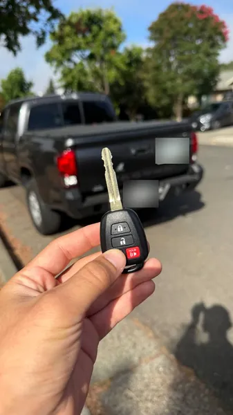 Toyota remote head key held behind a dark gray Toyota pickup