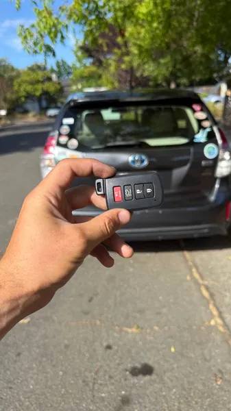 Toyota smart key held behind a gray Toyota hybrid hatchback