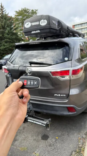 Toyota flip key held behind a gray Toyota SUV