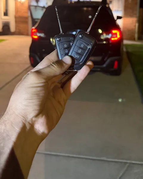 Two flip keys held behind an SUV at night